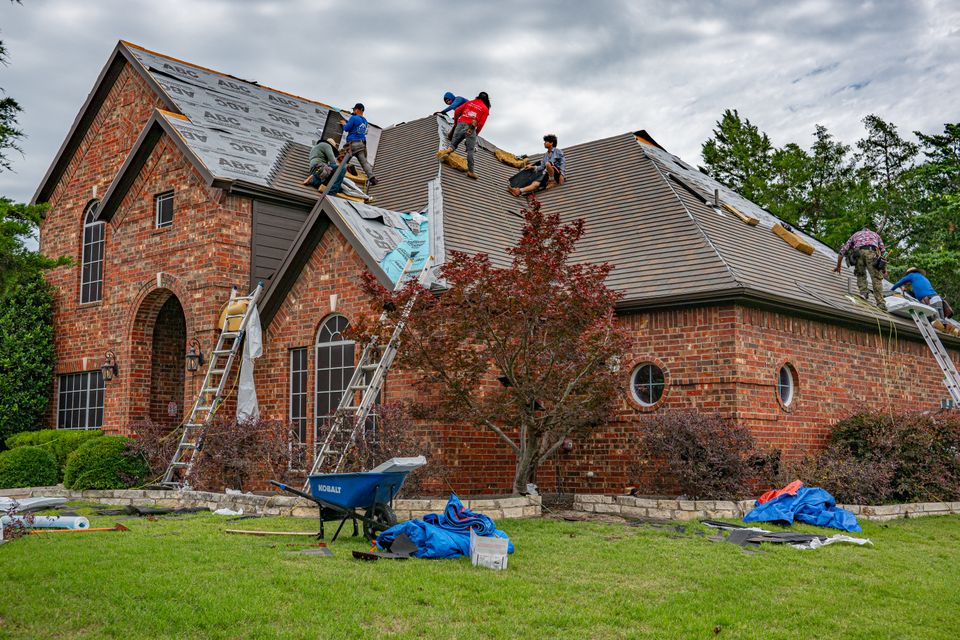 Stock view of a residential roofing crew working on a brick home
