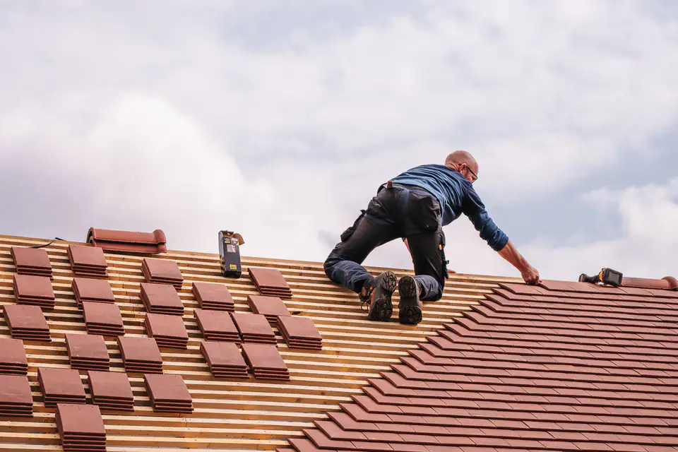 Roofer installing shingles on a residential roof